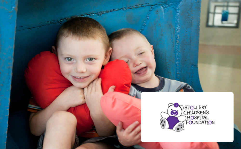 Two young boys smiling together hugging heart cushions.
